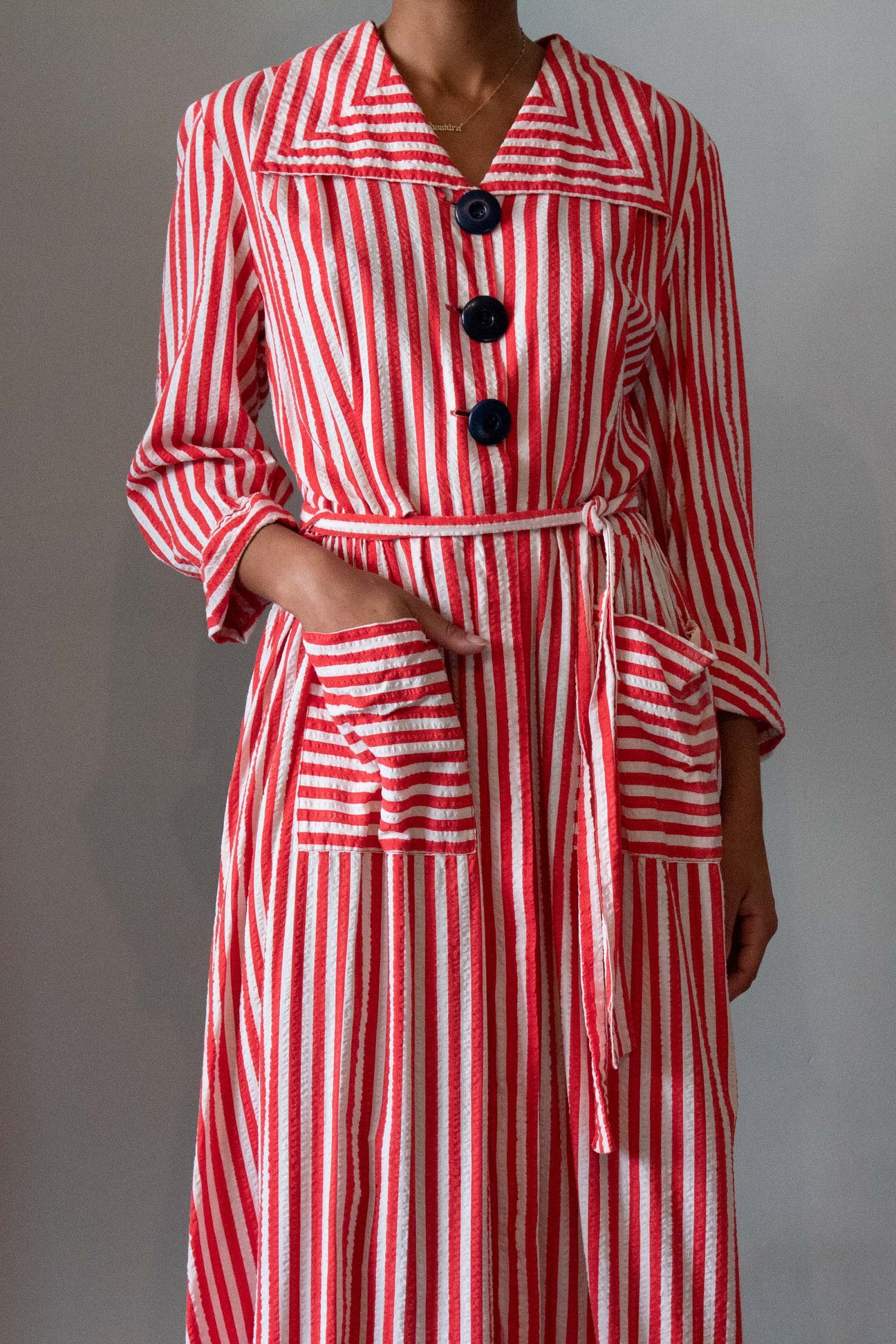 1940s candy cane-striped seersucker dress with waist tie, bold buttons and front pockets.